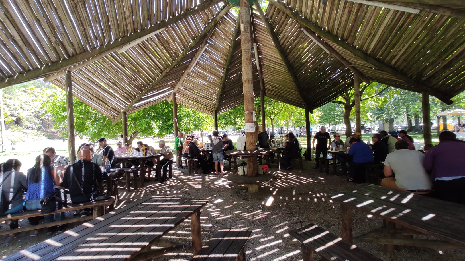 Fotografia tirada durante a sardinhada no Parque de Merendas da Barosa, onde é possível ver-se os participantes sentados em redor das diversas mesas existentes no espaço 