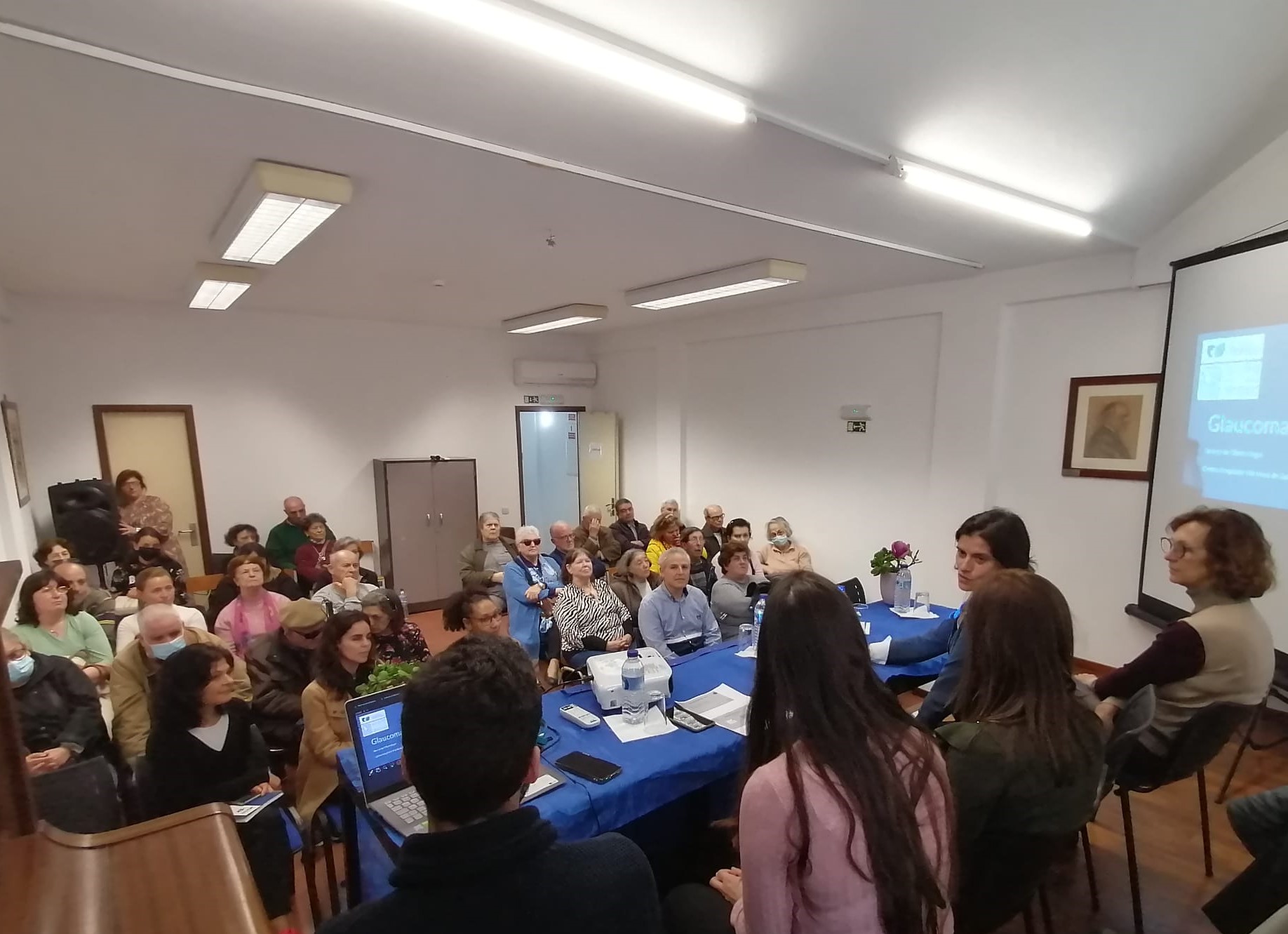 Fotografia geral tirada durante a sessão de esclarecimento sobre o Glaucoma onde é possível ver-se a plateia e, de costas, a equipa do Centro Hospitalar de Gaia e Espinho.