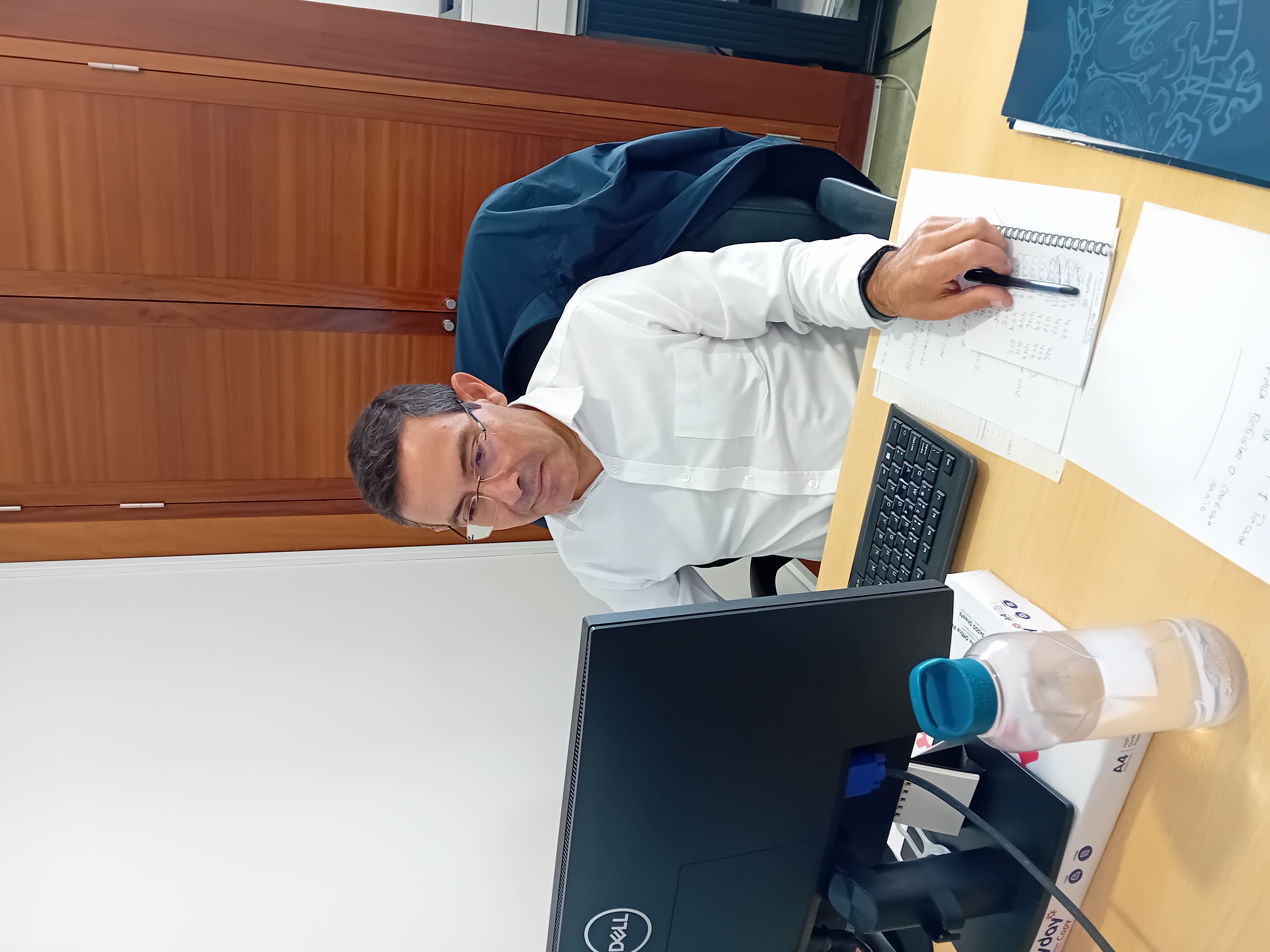 José Luís Cabral sentado no seu posto de trabalho. Na fotografia é possível ver-se um ecrã de computador, um teclado, algumas folhas e uma garrafa de água.