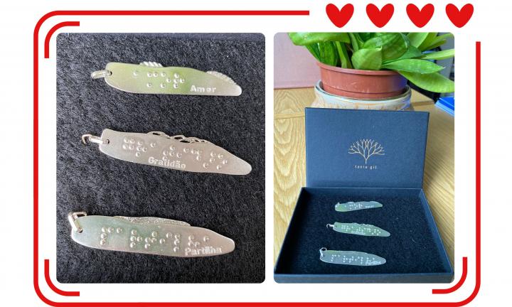Composição de imagem com duas fotografias dos pendentes de prata com Braille. Em redor das fotos está uma moldura em vermelho que no canto superior direito tem quatro corações.  