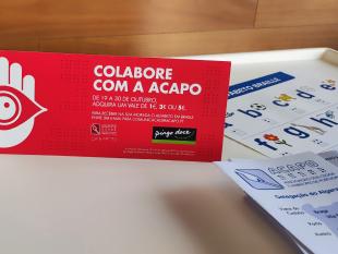 Placa publicitária do Pingo Doce alusiva à campanha, folhetos informativos sobre a nossa Delegação do Algarve e alfabetos Braille.