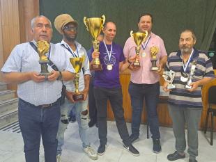 Segurando as taças ou troféus, os vencedores dos torneios pousam sorridentes para a fotografia. Entre os vencedores, está Paulo Santos, Presidente da Direção da Delegação de Lisboa que segura os troféus de dominó e bilhar.