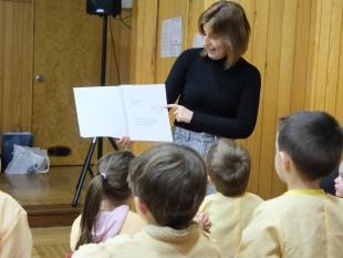 Carina Ferreira, Diretora Técnica da Delegação de Vila Real, com o livro “O meu livro de Lengalengas” na mão durante a ação de sensibilização, demonstrado a utilização simultânea do Braille e dos caracteres ampliados. 