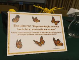 Cartão com imagens de borboletas e o seguinte texto - Escultura: “Representação de uma borboleta construída em arame”. Autora: Helena Ascenção, realizado na disciplina de Oficina de Artes. Orientação: professor e Escultor Rui Venâncio da ESFF