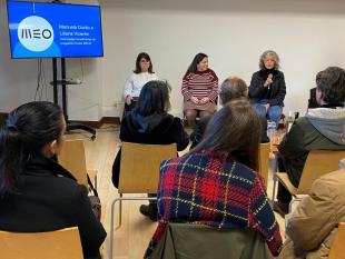 Sentadas, Marta Vitorino, Liliana Vicente e Manuela Durão durante a intervenção relativa ao projeto Pontos MEOS. Ao lado delas vê-se um ecrã com a projeção do logotipo da MEO.