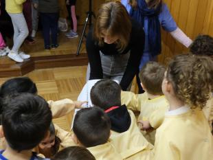 Várias crianças do jardim de infância a tatear com curiosidade o Braille do livro "O meu livro de Lengalengas" que está na mão da Diretora Técnica da Delegação de Vila Real, Carina Ferreira.