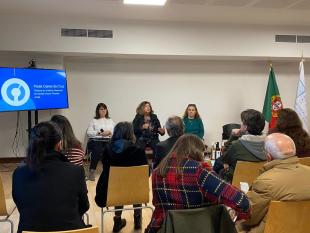 Sentadas, Marta Vitorino, Paula Caires da Luz e Carla Pereira durante a intervenção sobre integração profissional. Ao lado deles vê-se um ecrã com a projeção do logotipo do Instituto Nacional de Saúde Dr. Ricardo Jorge
