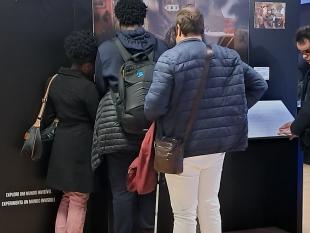 De costas, grupo de visitantes descobre através do tato a fotografia "Sábado à noite ao estilo de pandemia", por Ilvy Njiokiktjien