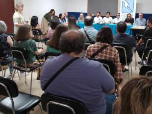 Fotografia tirada do fundo da sala vendo-se de costas os participantes na sessão "Parcerias que incluem". Ao fundo vê-se a mesa dos oradores e um roll up com o logotipo da ACAPO.