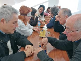 Duplas a jogar com os protótipos do Ludusfidelis, elaborado com materiais reciclados – caixas de ovos e tampas ou caricas, e com numeração em Braille. Na primeira dupla está Jaime Oliveira, Secretário da Direção da Delegação do Porto.