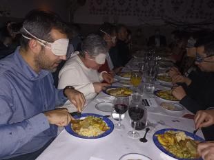 Participantes no jantar às escuras, de olhos vendados, durante a refeição.