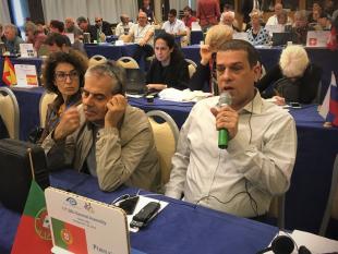 Vista geral da sala. Tomé Coelho e Rodrigo Santos em primeiro plano. Rodrigo Santos fala para o microfone que segura na mão. 