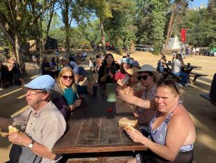 O grupo sentado numa mesa de madeira, a comer sandes de porco no espeto e a beber refrescos em copos de barro