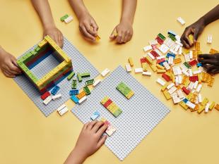 Fotografia onde é possível ver as mãos de quatro crianças a brincar com as peças LEGO® Braille Bricks.