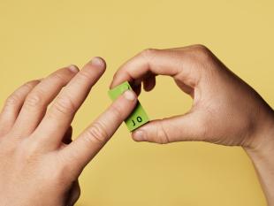 Fotografia onde é possível ver as mãos de uma criança a descobrir, através do tato, uma das peças do kit LEGO® Braille Bricks.