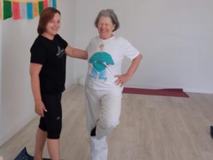 Assistente Pessoal e Beneficiária em contexto de assistência, a sorrirem para a câmara fotográfica, no decorrer de uma aula de Yoga