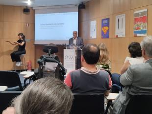 No púlpito, Carlos Carvalho, intervém na sessão de encerramento. Na fotografia é possível ver-se também uma tela onde está projetada uma apresentação e a intérprete de LGP que está também no palco.