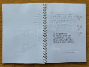 Livro aberto numa das lengalengas vendo-se o texto em caracteres ampliados e em Braille e o desenho de três pombas.