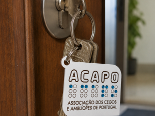 Fotografia aproximada vendo-se umas chaves na fechadura de uma porta. As chaves estão colocadas no porta-chaves da ACAPO. 