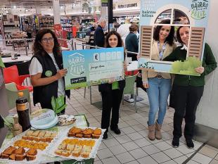 À esquerda, duas funcionárias da loja estão a segurar o cheque simbólico, no valor de 985,00€. À direita, Dulce Espincho, Assistente Social, em representação da Delegação do Porto, e uma representante da loja Pingo Doce.