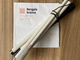 Guardanapo com a palavra "Bengala Branca". Sobre o guardanapo está colocada uma bengala dobrada.