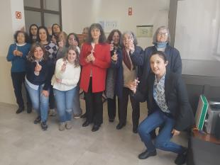 Equipa técnica e Associadas pousam sorridentes para a fotografia numa das salas da Delegação, segurando na mão o batom que receberam.
