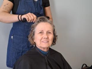 Carolina Dias, Secretária da Direção da Delegação de Aveiro,  pousa sorridente para a foto enquanto a cabeleireira a penteia. 